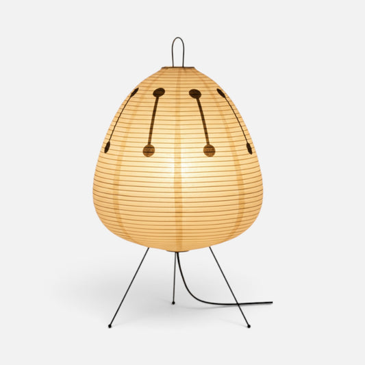 Elvora egg-shaped rice paper floor lamp with a warm glow and black tripod base featuring decorative dark accents